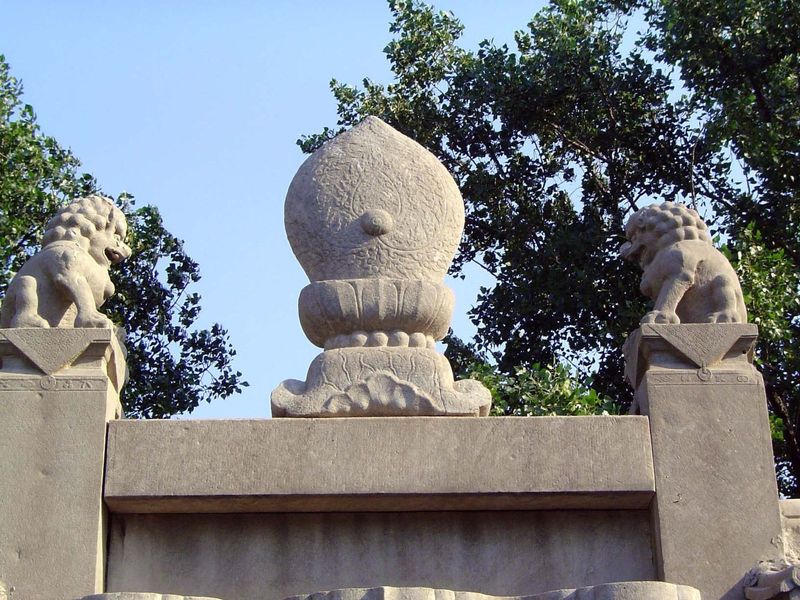 The central ornament is variously described as a ball wrapped in flame, as a peach—a Taoist symbol of longevity—or as a modified Tibetan Bud