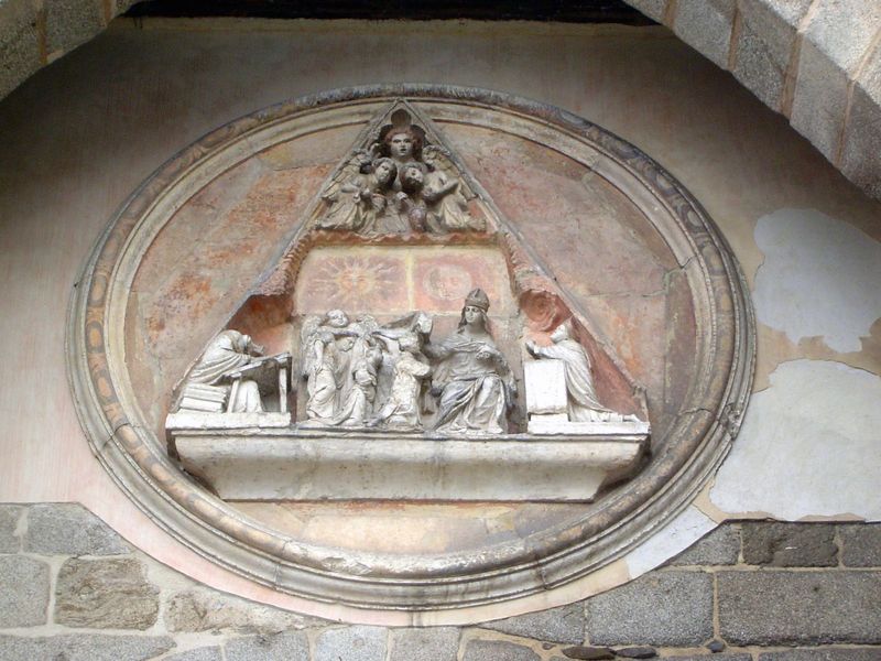 The triangular medallion is the scutcheon of Toledo's cathedral and shows the ordination of Ildephonsus, the bishop of Toledo and a disciple