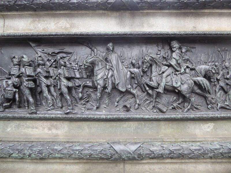 The base of the statue has a bronze version of the Battle of Waterloo.