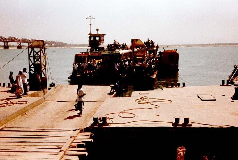 Immediately downstream, a crowded ferry handles vehicular traffic.