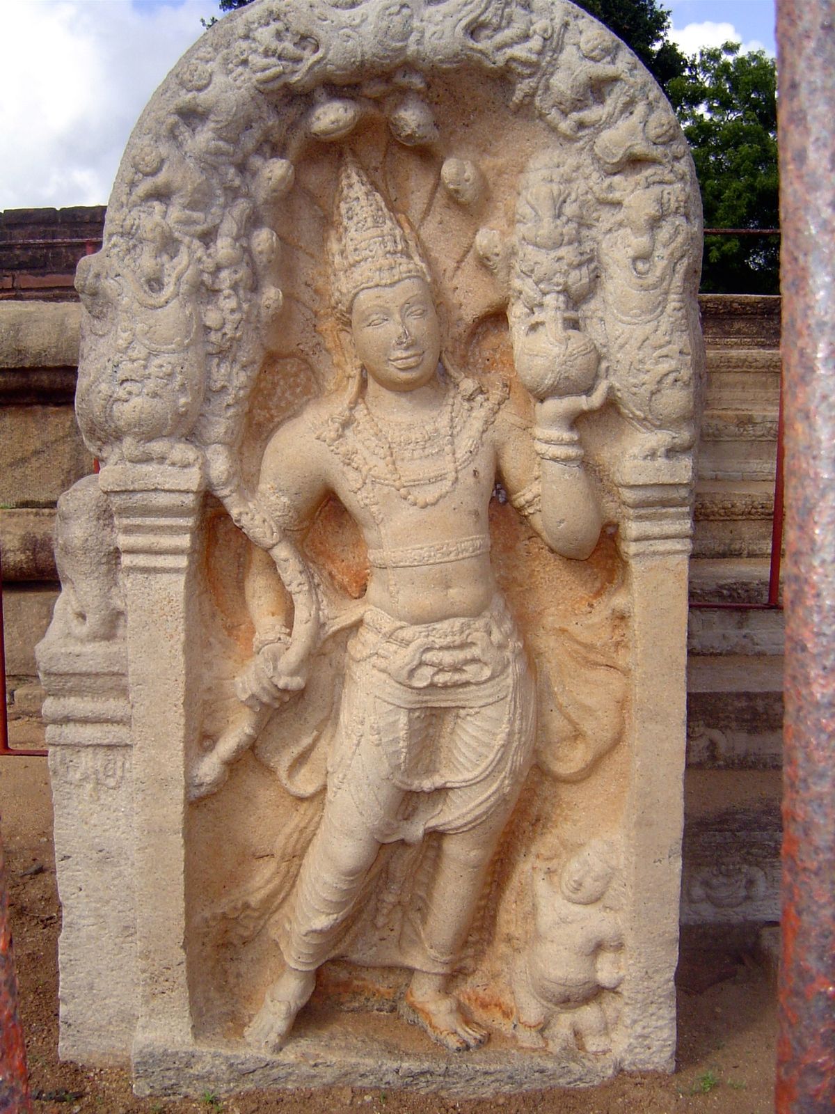 There are different guards; this one is a nagaraja, an anthropomorphized king cobra. He holds a pot of plenty, a punkala.