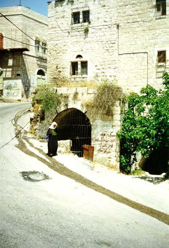 Asphalt remained on the steep ridge-crossing road. The Church of the Nativity is just off to the upper left. The woman is passing the "ein,"