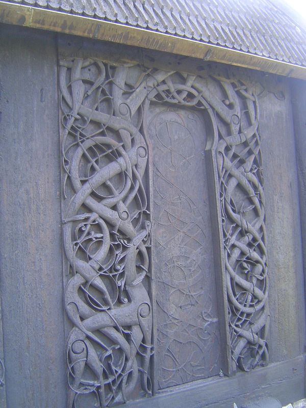 On the north side of the church, there's an old doorway framed by two carved jambs. The image appears to show creatures "Urnes beasts" bitin