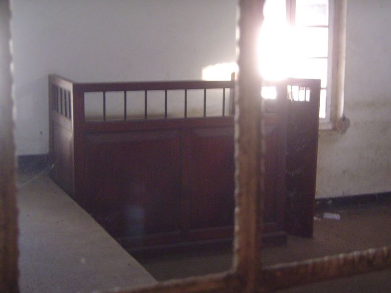 The court-room dock, seen through a dusty window.