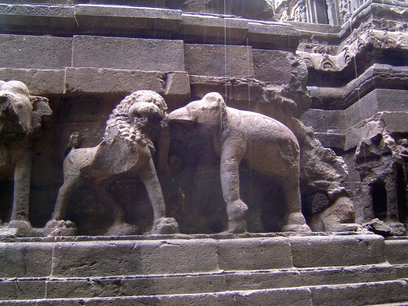 At the base of the temple, elephants fight overscale lions.