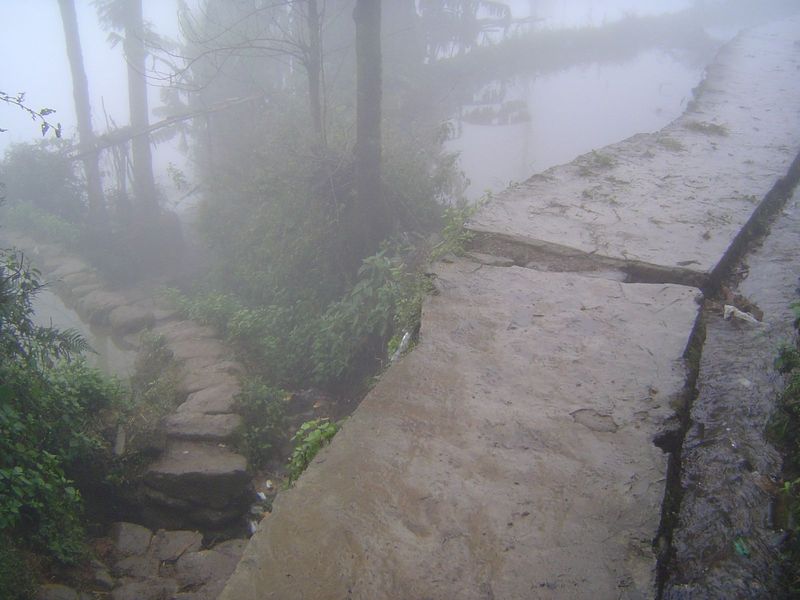 Farther downhill, the village ends and gives way to misty fields.