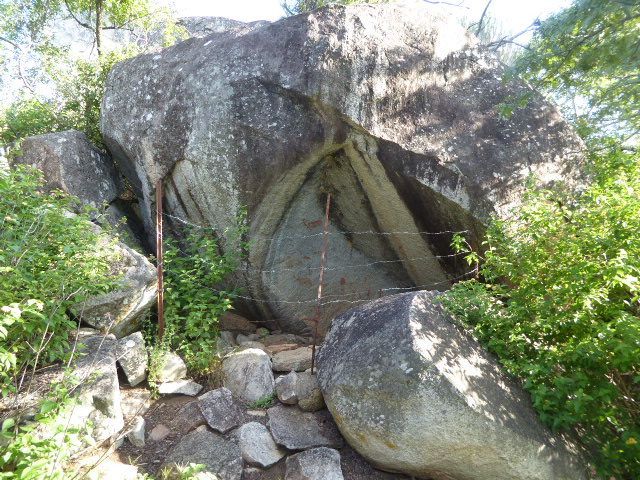 Semi-protected by T-bar and barbed wire, there are paintings on the rock.