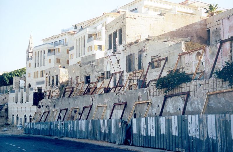 On the edge of collapse, old buildings await their conversion into the facades of new buildings.