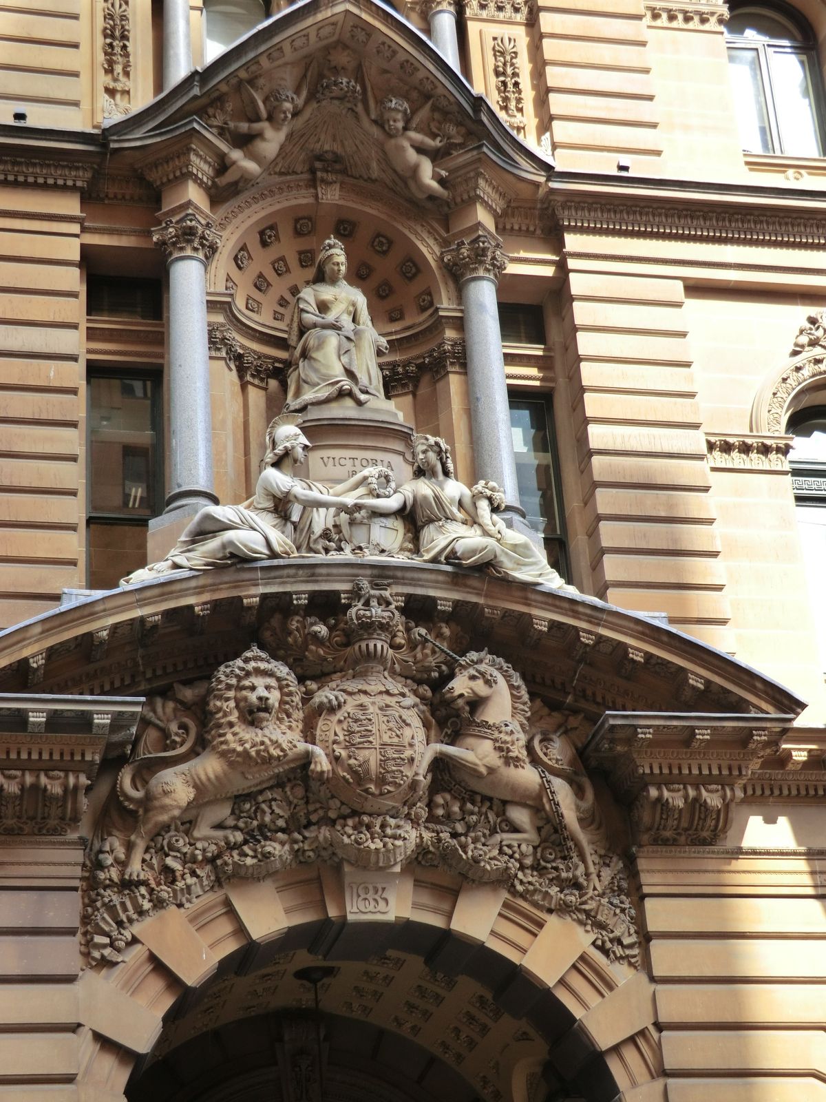 Victoria sits above the royal coat-of-arms and two young ladies identified only as run-of-the-mill "allegorical figures." Wisdom and Plenty,
