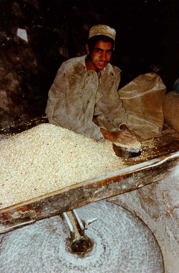 On another day, the mill was open, and the stone was spinning fast as the boy funneled corn down to it.