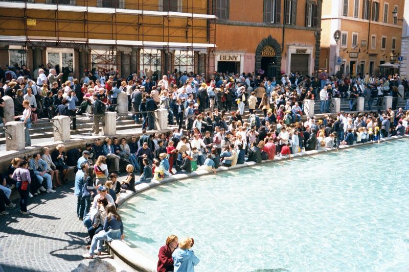 A few blocks away, crowds at the Trevi Fountain wait for something.