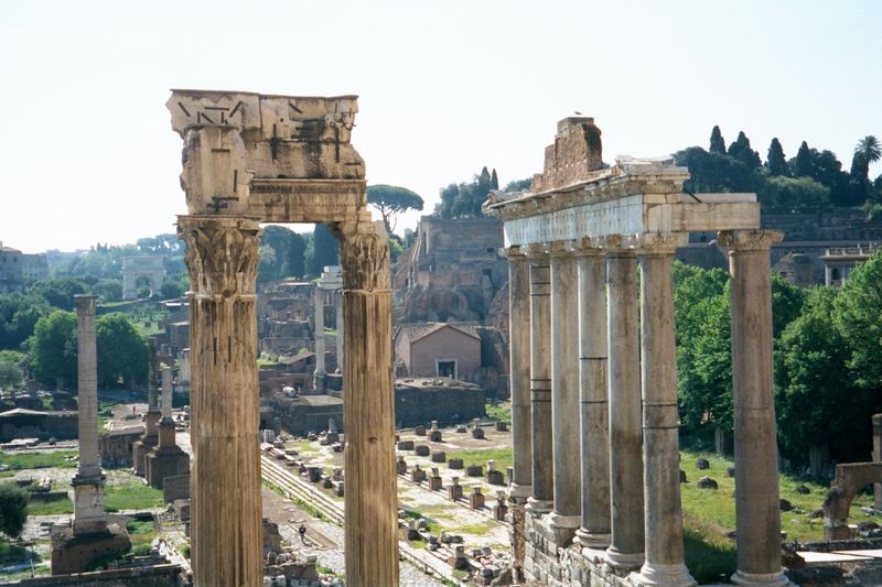 Looking west from the Capitoline back to the Arch of Titus in the left background. In the foreground, three corner columns one is almost com
