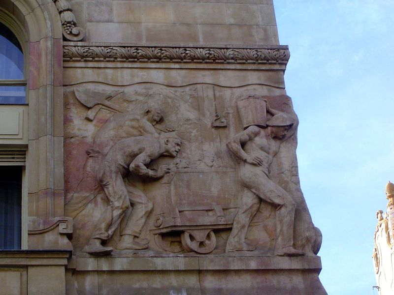 Alpar's background shows in these details on the bank. The reliefs are by Karoly Sennyei and show a range of grim but wealth-producing activ
