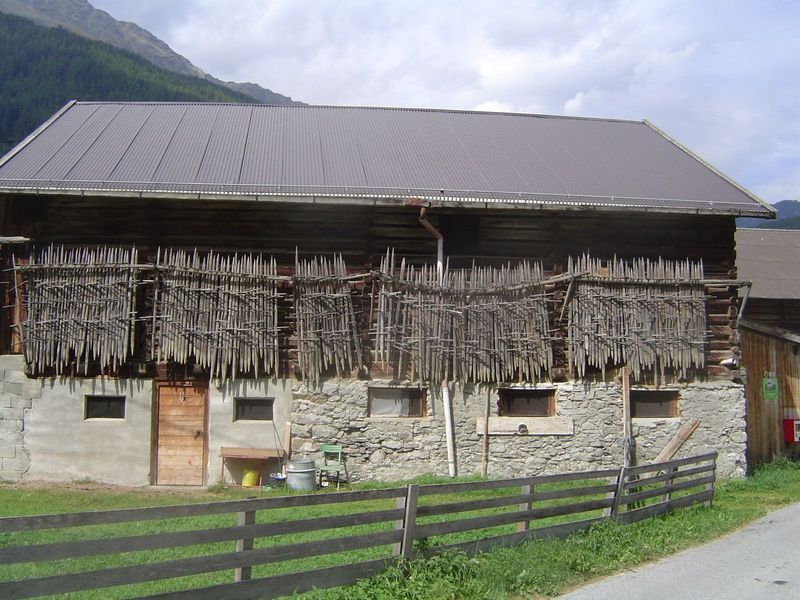 Hay is stacked around stakes that are themselves neatly arranged for safekeeping.