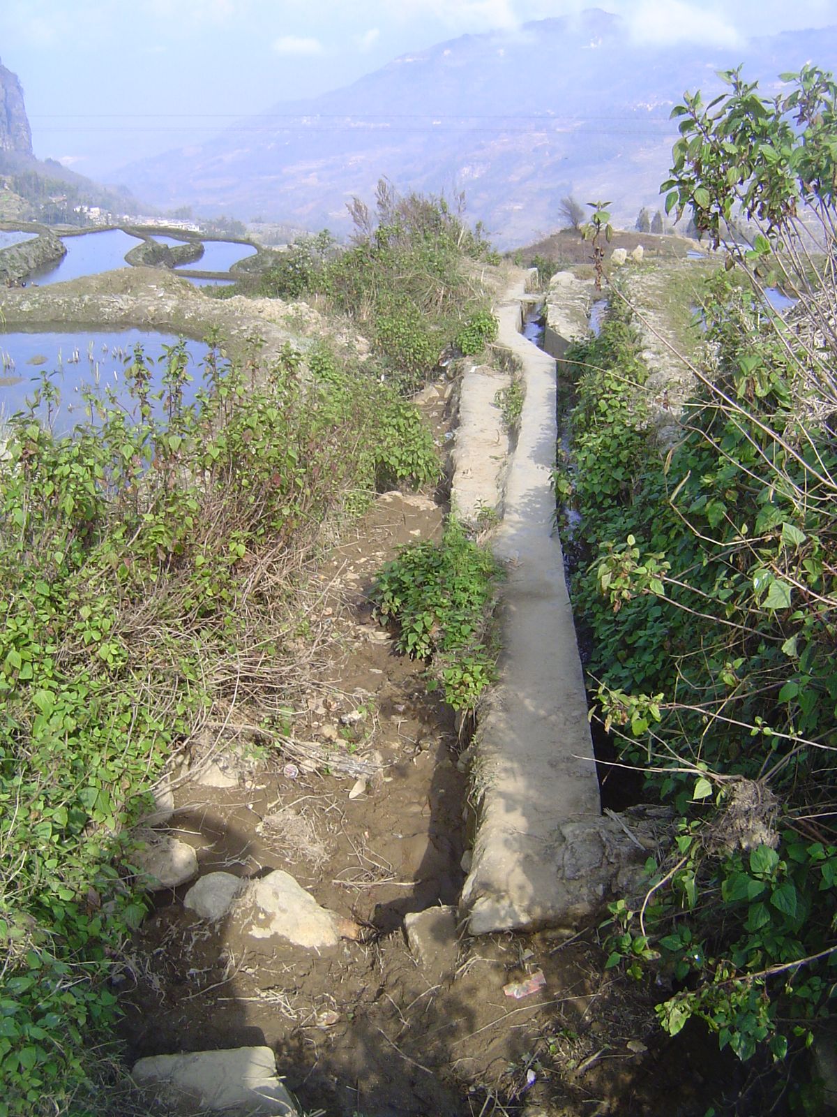 A forking concrete channel takes off to the right, while the main channel drops into a gulley.