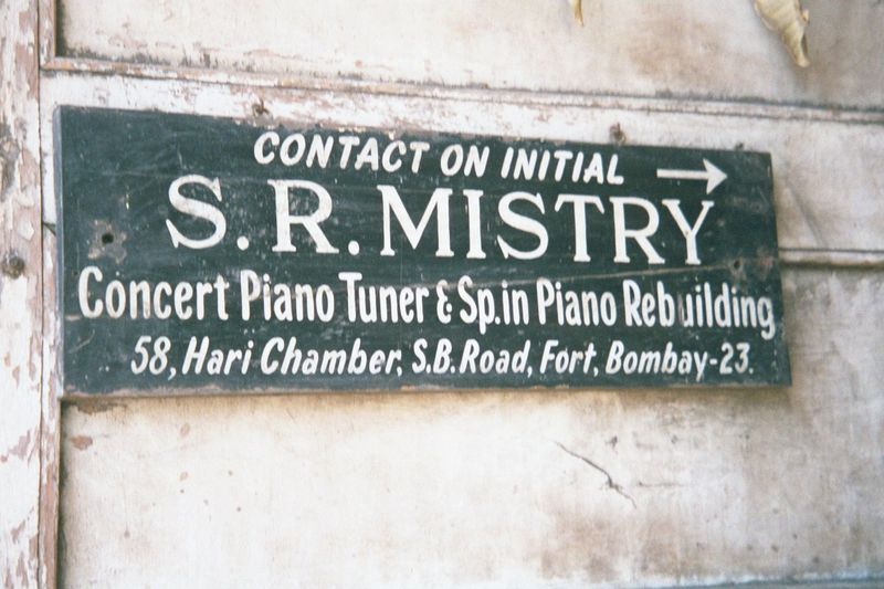 The shop is too small to hold a grand piano. A few actions sit on shelves; an upright awaits a customer.