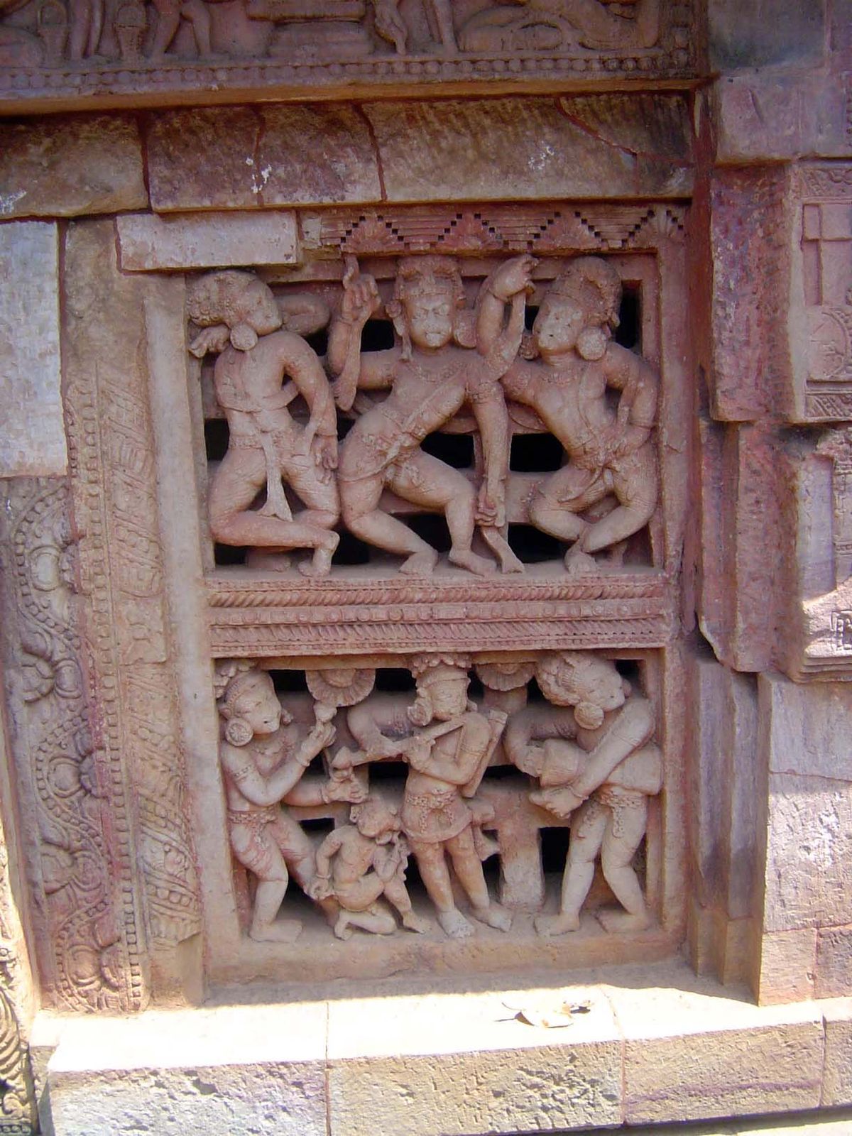 A window in the porch has a grill carved into dancers and musicians.
