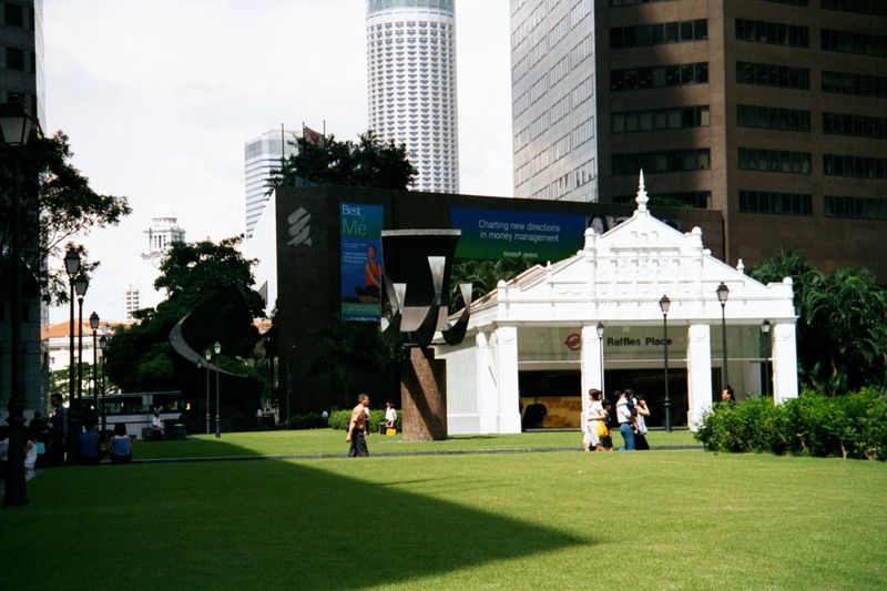 The shadowy mass of the Standard and Chartered tower stands above the fake-old Raffles Place subway station.