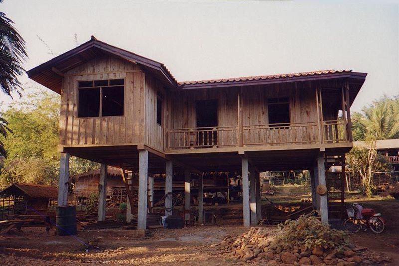 A new house with concrete foundation posts and manufactured railings and roof tiles. In short, modern, even without the motorcycle.