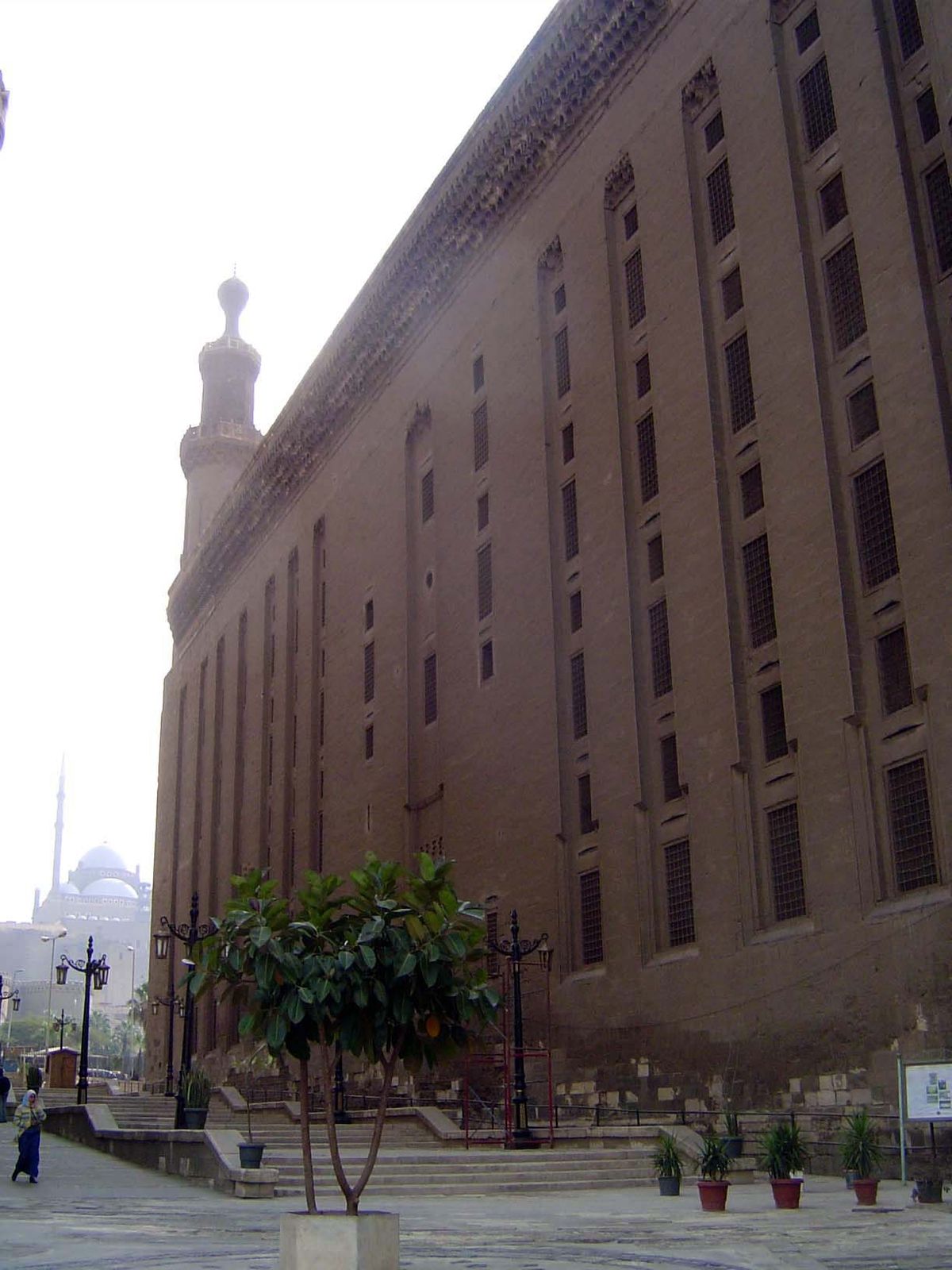 The outside of the building, with windows indicating the cells once occupied by students; in the distance, the Mosque of Muhammad 'Ali.